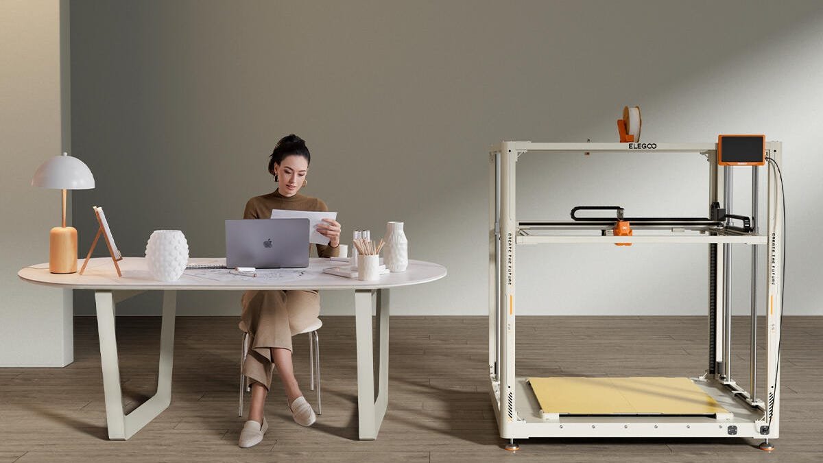 GigaStorm Orange 3d printer next to a woman at a desk